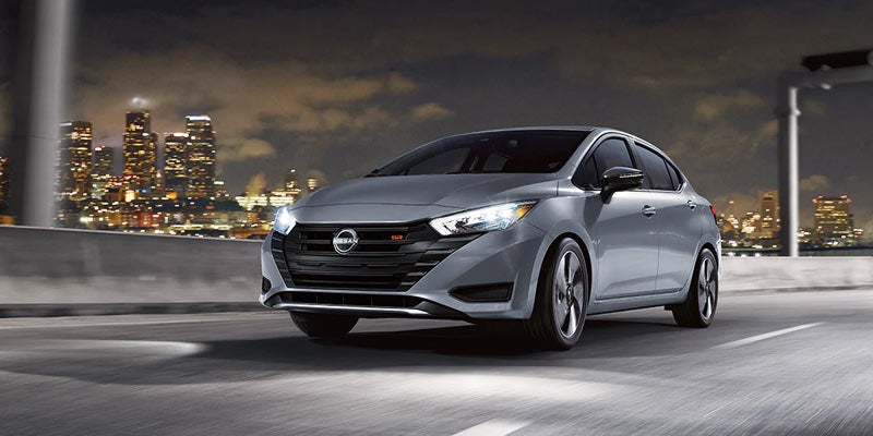 A 2024 Nissan Versa driving down a highway in the city at night in Mayfield Heights, OH