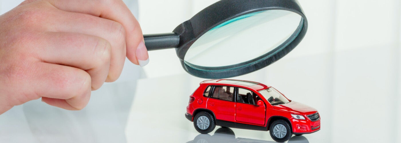 image of someone holding a magnifying glass overtop of a small toy car
