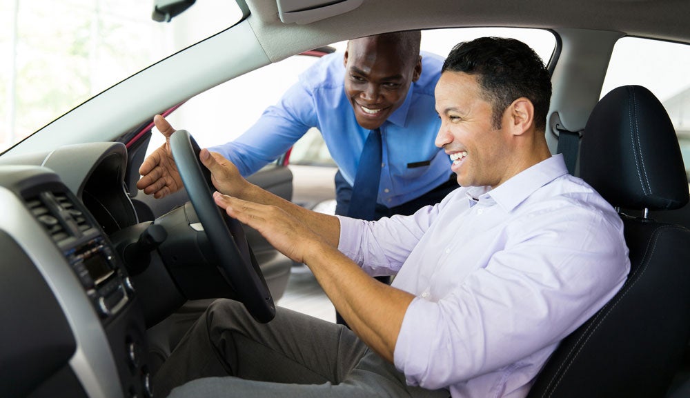 image of man sitting in drivers seat with a salesman beside him